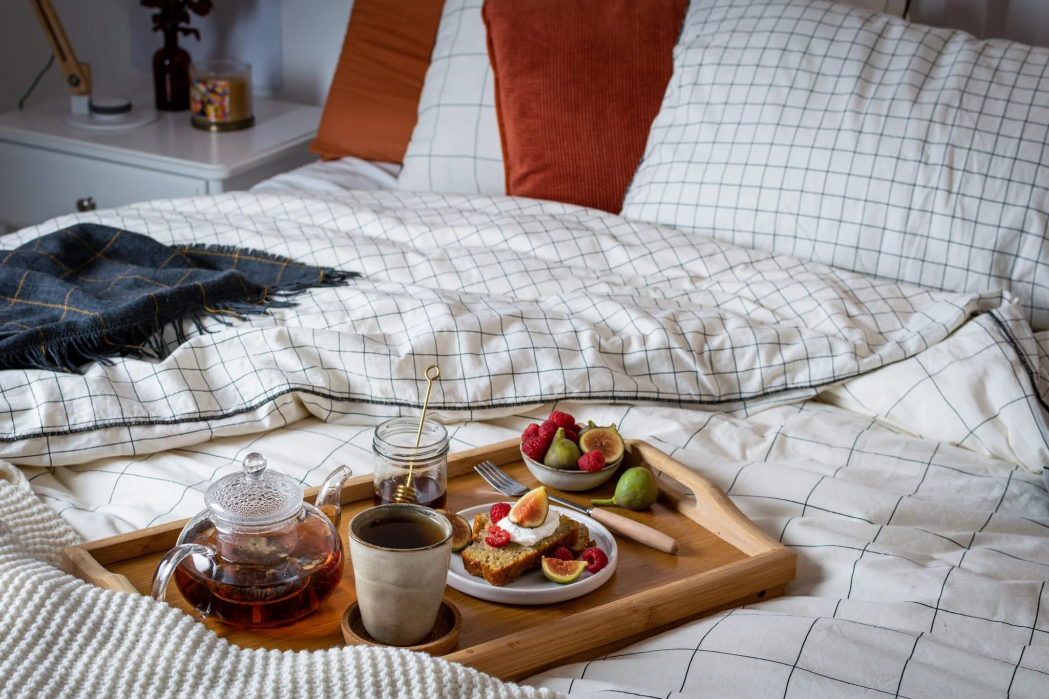 Weißes Hygge-Bett mit roten Kissen.