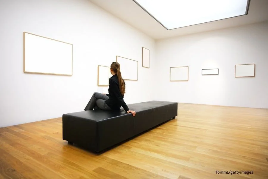 Frau auf Bank betrachtet Bilder in Ausstellung