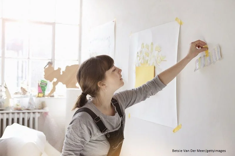 Frau klebt Bilder an die Wand