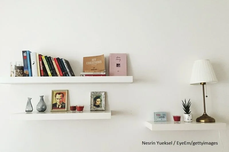 Schlichtes weißes Regal mit Büchern, Vasen udn Bildern.