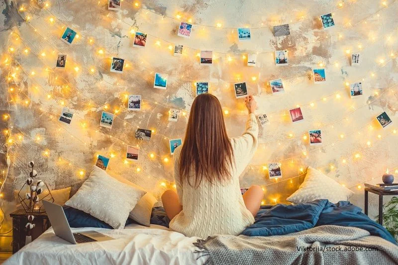 Junge Frau hängt Polaroid Bilder und Lichterketten an einer Schnur auf